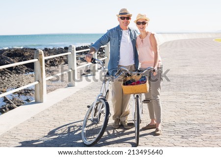 Happy casual couple going for a bike ride on the pier on a sunny day