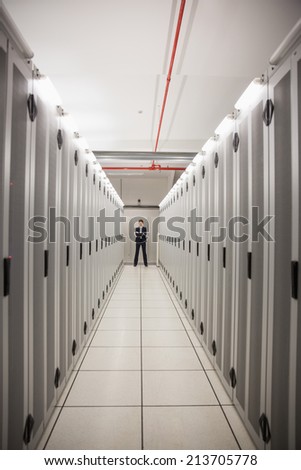 Serious technician standing in server hallway in large data center