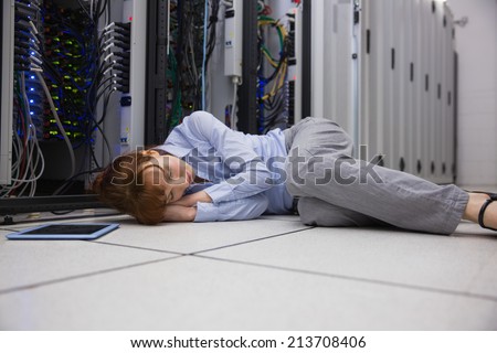 Exhausted technician sleeping on the floor in large data center