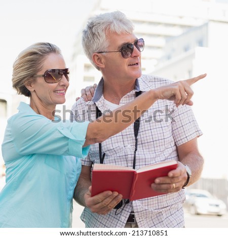 Happy tourist couple using tour guide book in the city on a sunny day