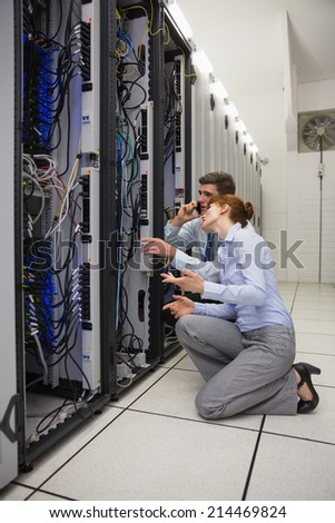 Team of technicians kneeling and looking at servers in large data center