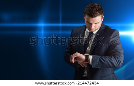 Handsome businessman checking the time against futuristic glowing black background