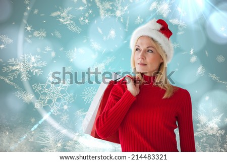 Happy festive blonde with shopping bags against blue snow flake pattern design