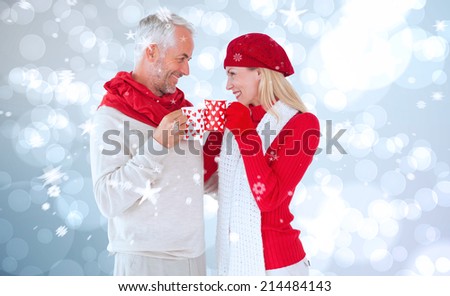 Happy winter couple with mugs against light glowing dots design pattern