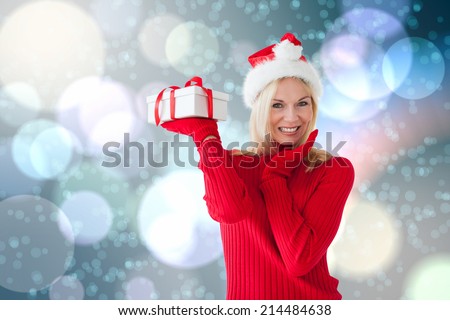 Happy festive blonde with gift against light glowing dots on blue