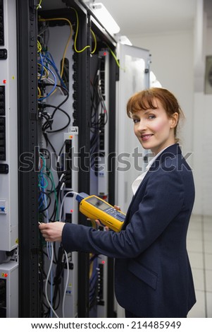 Happy technician using digital cable analyzer on server in large data center