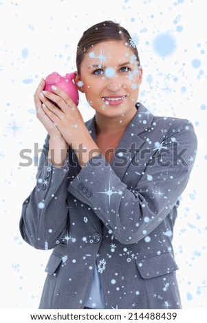 Smiling bank clerk shaking piggy bank against snow falling