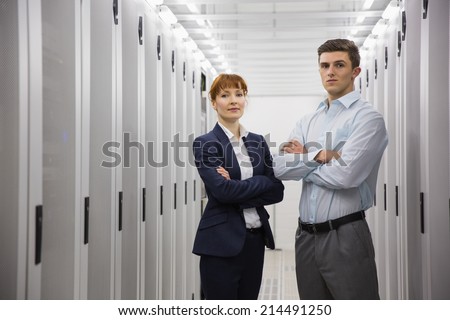 Team of computer technicians looking at camera in large data center