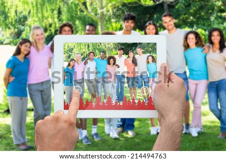 Hand holding tablet pc against friends standing with arms around