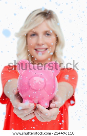 Pink piggy bank held by a smiling attractive woman against snow falling
