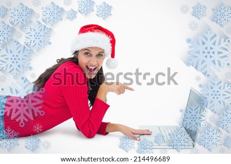Beautiful festive woman pointing to laptop against snowflake frame