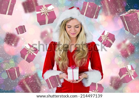 Pretty girl in santa outfit holding gift against light glowing dots on blue
