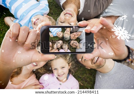 Hand holding smartphone showing extended family lying in circle at park