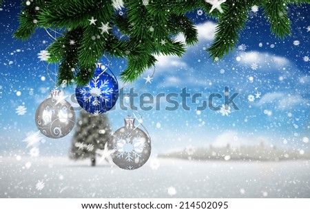 Composite image of christmas decorations against fir tree in snowy landscape
