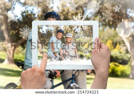 Hands holding tablet pc against elderly couple with their bikes