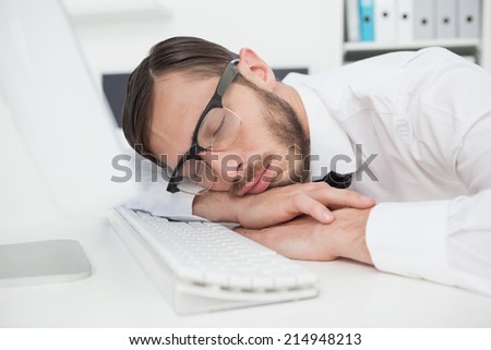 Nerdy businessman sleeping on keyboard in his office