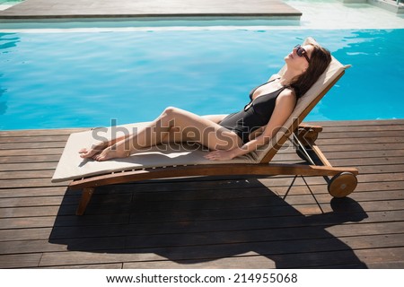 Side view of beautiful young woman in bikini relaxing by swimming pool