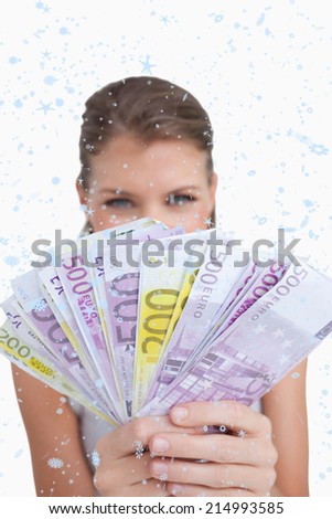 Portrait of a cute woman showing bank notes against snow falling
