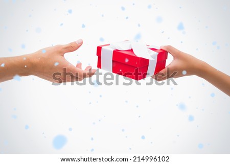 Woman passing man a gift against snow falling