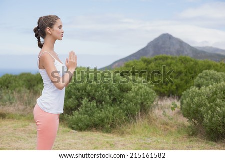 Healthy and beautiful woman with hands joined standing on countryside landscape