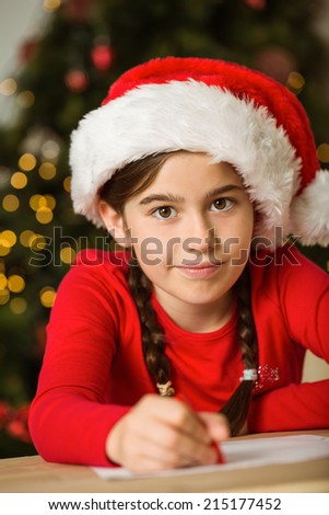 Little girl writing letter to santa at christmas at home in the living room