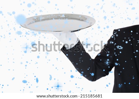Hand with white gloves holding a silver tray against snow falling