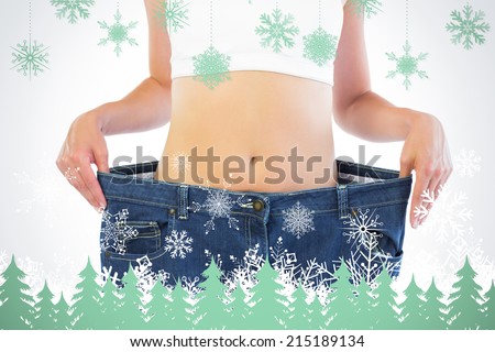 Close up of confident thin blonde wearing too big trousers against snowflakes and fir trees in green
