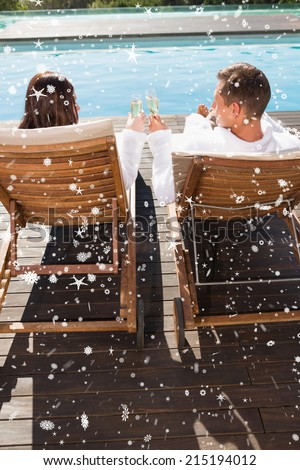 Couple toasting champagne by swimming pool against snow falling