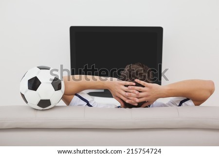 Rear view of a soccer fan watching tv