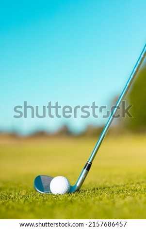 Close-up of golf ball with golf club on grassy land against clear blue sky during summer, copy space. unaltered, golf course, sport and nature concept. 商業照片 © 