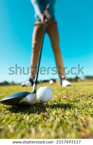 Low section of african american young man aiming golf ball with club against clear sky in summer. copy space, low angle view, golf, golf course, unaltered, sport and weekend activities concept. 商業照片 © 
