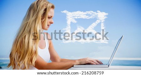 Composite image of pretty blonde using her laptop at the beach against cloud email