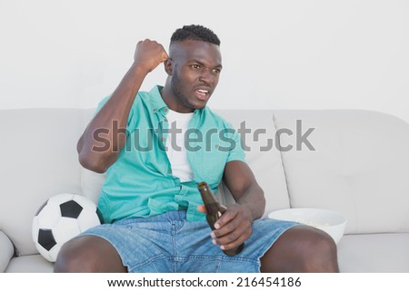 Concentrated soccer fan cheering while watching tv