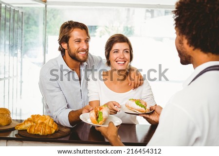 Barista serving two happy customers at the coffee shop
