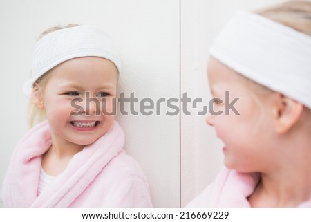 Cute little girl looking in mirror at home in the bathroom