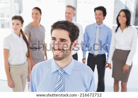 Business man smiling at work with staff behind him