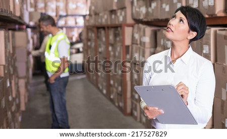 Pretty warehouse manager checking inventory in a large warehouse
