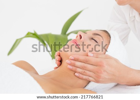 Close up of an attractive young woman receiving facial massage at spa center