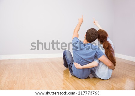 Couple sitting on floor together pointing upwards