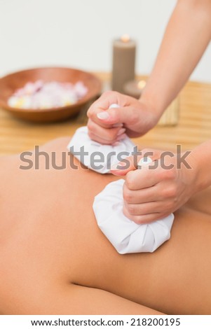 Woman enjoying a herbal compress massage in the health spa