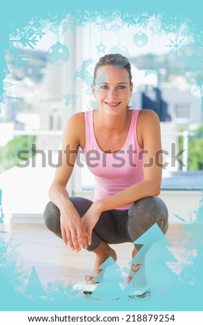 Woman crouching on weighing scale in gym against christmas frame