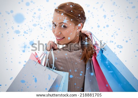 Back view of smiling woman with shopping bags against snow falling