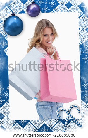 A woman looking back at the camera is carrying shopping bags over her shoulder against christmas frame