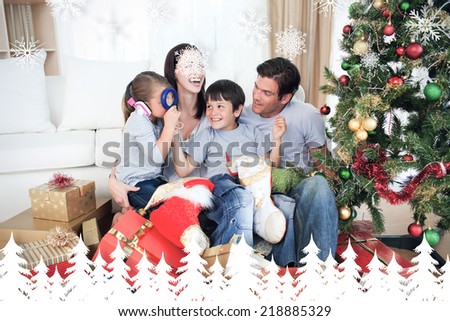 Happy family playing with Christmas gifts against fir tree forest and snowflakes