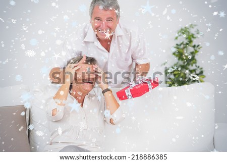 Composite image of Old man hiding eyes of his wife for a gift against snow