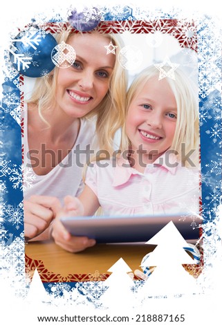 Mother using tablet pc with her daughter against christmas themed frame