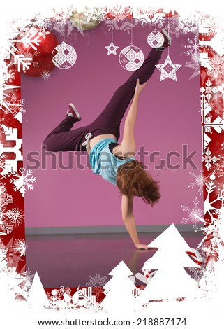 Pretty break dancer doing handstand with one hand against christmas themed frame