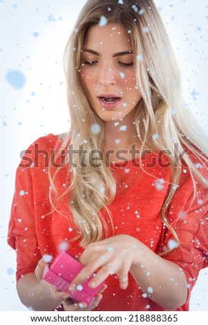Composite image of Surprised woman opening her gift with snow falling