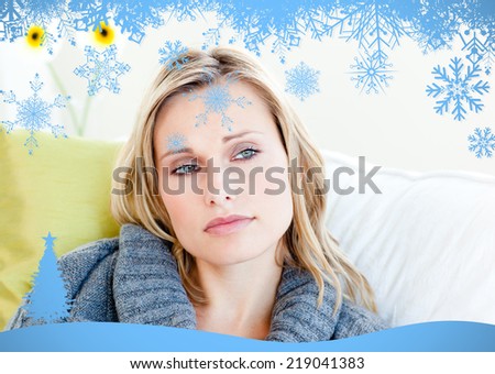 Exhausted woman lying on the sofa with a grey pullover against snow flake frame in blue