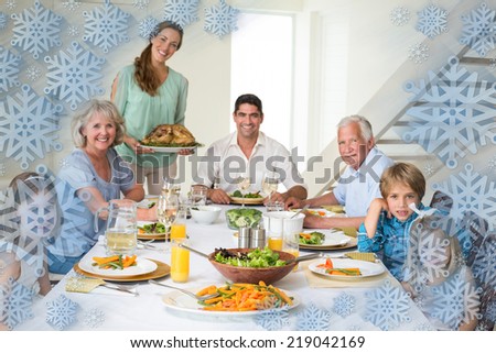 Family having meal at dining table against snowflake frame